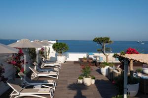 a row of chairs and umbrellas on a patio with the ocean at La Chiaja art&relais in Castellammare di Stabia