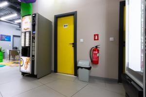 a yellow door in a room next to a fire extinguisher at Green Cube Capsule Hostel in Sofia +50 photos