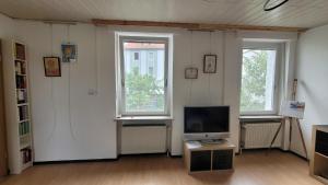 a living room with a tv and two windows at Ferienwohnung bei Stettens in Bad Neuenahr-Ahrweiler +9 photos
