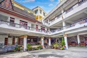 a large building with balconies and tables in a courtyard at Collection O near Museum Pusaka Karo formerly 3 Berastagi in Berastagi