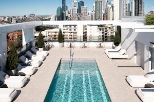 a swimming pool on the roof of a building with lounge chairs at The Alva Hotel Brisbane, Vignette Collection by IHG in Brisbane