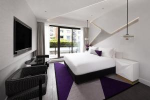 a bedroom with a bed and a tv and a chair at The Alva Hotel Brisbane, Vignette Collection by IHG in Brisbane