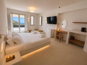 a bedroom with a bed and a desk and a television at Vespera Private Luxury Suites in Santorini