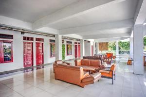 a living room with leather furniture and red doors at Collection O near Museum Pusaka Karo formerly 3 Berastagi in Berastagi
