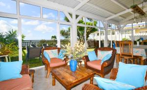 a screened in porch with chairs and a wooden table at THE BAY in Trou d'Eau Douce