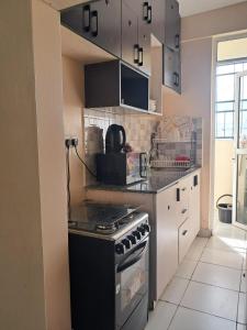 a kitchen with a stove and a counter top at Cozy 2 BR with 3 Beds, AC & Hot Shower at Buxton Point Apartments Off RG Road Gate A in Mombasa