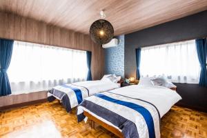 two beds in a bedroom with blue walls and windows at Gran kodachi in Fujikawaguchiko