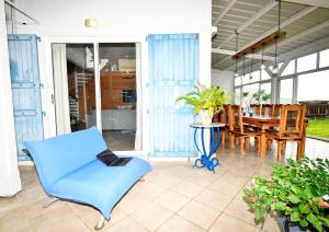 a porch with a blue chair and a table at THE BAY in Trou d'Eau Douce