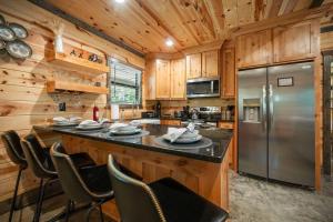 a kitchen with a large island with chairs and a refrigerator at Private Escape| Hot tub| Fire Pit| Trail Access in Broken Bow