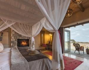 a bedroom with a large bed with a fireplace at Onguma The Fort in Namutoni Gate