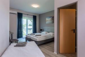 a bedroom with two beds and a sliding door at Holiday Hotel Siófok in Siófok