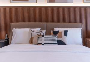 a bed with white sheets and pillows in a bedroom at Stunning Oceanfront Studio Stay - Blue Bay Walk Pool & Gym in Sharjah +22 photos