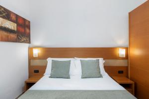 a bedroom with a white bed with two pillows at Hotel Moscatello in Rome