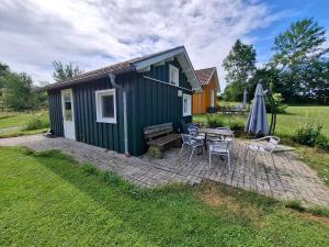 a green tiny house with a picnic table and an umbrella at Mitteltalhof in Kaufungen +22 photos