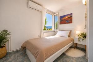 a white bedroom with a bed and a window at Little Villa - walk to the beach in Thessaloniki