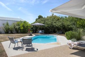 a swimming pool with chairs and an umbrella at Les Chambres De Miloly in La Jarrie