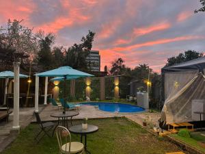 a backyard with a pool with tables and chairs at Hostal Sueños De Lujo in Talca