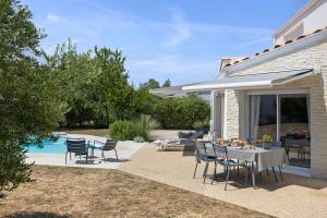 a patio with a table and chairs and a pool at Les Chambres De Miloly in La Jarrie