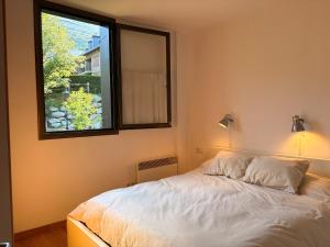 a bedroom with a white bed and a window at Con encanto, buena ubicación, confort y parking - Aüt 2 in Pla de l'Ermita