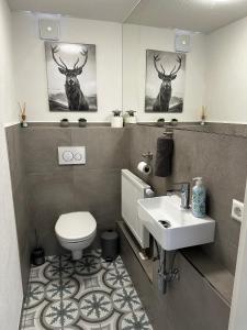 a bathroom with a toilet and a sink and two deer pictures at Bauernhofwohnung Friedrichshafen in Friedrichshafen +25 photos
