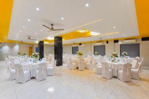 a banquet hall with white tables and white chairs at Ginger Somnath in Somnath