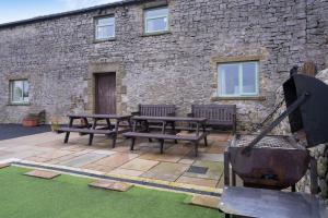 a patio with benches and a grill in front of a building at The Holmes Barn - Sleeps 16 - Pet friendly in Buxton