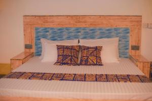 a large bed with a wooden headboard and pillows at Bahari Studio Apartment in Bwejuu