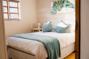 a bedroom with a bed with blue pillows at Jakaranda Cabin - Self Catering Apartment in Secunda