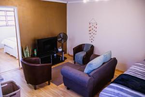 a living room with a couch and chairs and a television at Jakaranda Cabin - Self Catering Apartment in Secunda