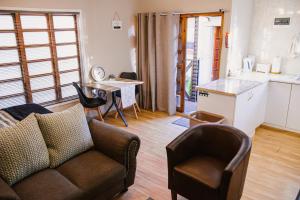a living room with a couch and chairs and a kitchen at Jakaranda Cabin - Self Catering Apartment in Secunda