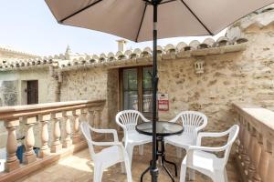 a table with white chairs and an umbrella on a balcony at Can Vallori in Sencelles