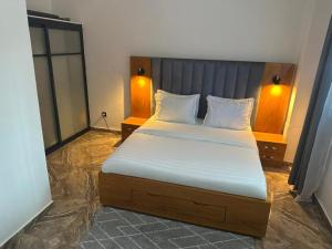 a bedroom with a bed with white sheets and two lamps at Bonapriso in Douala
