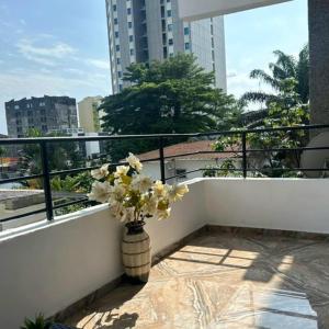 a vase filled with flowers sitting on a balcony at Bonapriso in Douala