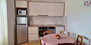 a small kitchen with a table and a refrigerator at Apartments Belmi in Barbat na Rabu