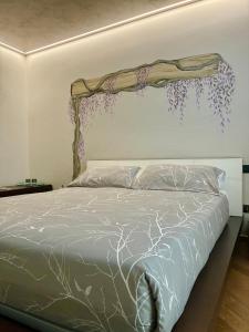 a bedroom with a bed with purple flowers on the wall at Antea Nuevo Sol Rooms and Breakfast in San Pellegrino Terme