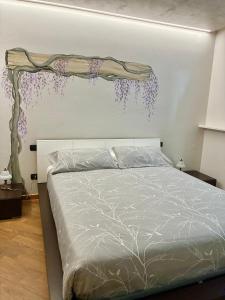 a bedroom with a bed with purple flowers on the wall at Antea Nuevo Sol Rooms and Breakfast in San Pellegrino Terme