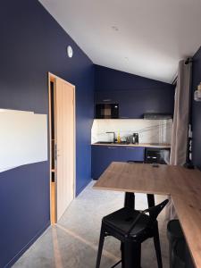 a kitchen with a wooden table and a blue wall at Studio Céleste - Clim - Parking gratuit - Proche CNPE Blayais in Braud-et-Saint-Louis