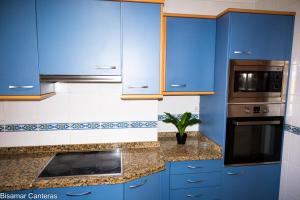 a kitchen with blue cabinets and a microwave at Brisamar Canteras in Las Palmas de Gran Canaria