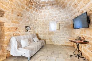 a living room with a couch and a tv at Trullo Sobba Llera by BarbarHouse in San Michele Salentino