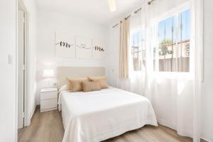 a white bedroom with a white bed and a window at CHALET 273 con PISCINA PRIVADA in Callao Salvaje