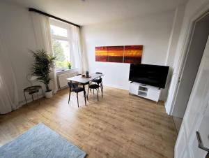a living room with a table and a flat screen tv at Tolle Moderne Altbau Wohnung in Hohenlockstedt +3 photos