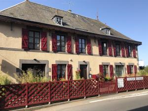 a building with red shuttered windows and a red fence at A l'Aube des Volcans in Charbonnières-les-Vieilles