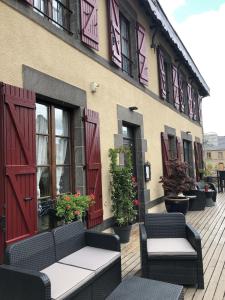 a building with red doors and chairs on a deck at A l'Aube des Volcans in Charbonnières-les-Vieilles