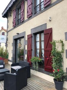 a building with red shutters on a patio at A l'Aube des Volcans in Charbonnières-les-Vieilles