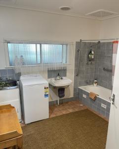 a small bathroom with a sink and a tub and a refrigerator at Barossa Suites on Basedow in Tanunda
