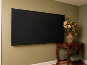 a flat screen tv on a wall with a vase of flowers at The Country Barn in Port Alberni