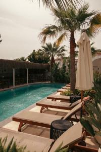 eine Reihe von Liegestühlen und ein Pool mit Sonnenschirm in der Unterkunft Art otel in Alacati + 107 Fotos