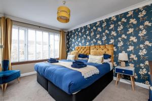 a bedroom with a blue bed with floral wallpaper at Driftwood - Crail in Crail