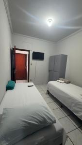 a room with two beds and a television in it at BG Hospedagens in Paracatu