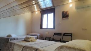 a bedroom with two beds and a window and two chairs at Casa Rural Chuan Murillo in Bestué